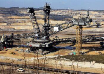 Bucket-wheel excavator in open-pit mine, surrounded by terraced excavation and machinery.