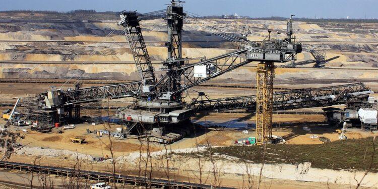 Bucket-wheel excavator in open-pit mine, surrounded by terraced excavation and machinery.