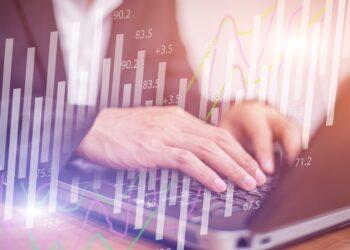 Person typing on laptop with overlaid bar and line charts indicating data analysis activity.