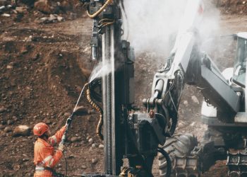 man in orange shirt and black pants holding black rifle