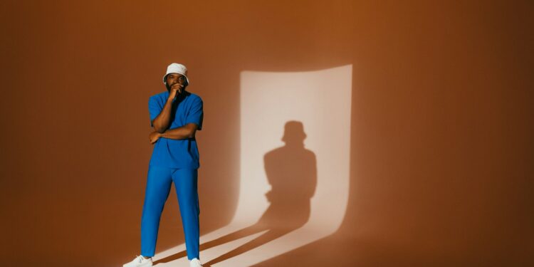 A person poses in front of a shadow.