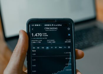 a person holding a cell phone in front of a laptop