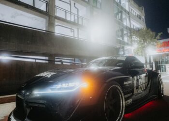 A black sports car is illuminated at night.