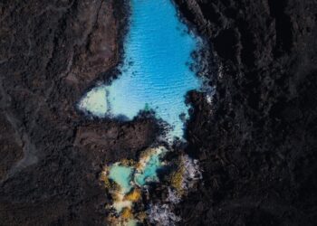 Turquoise water pools contrast dark volcanic rock.