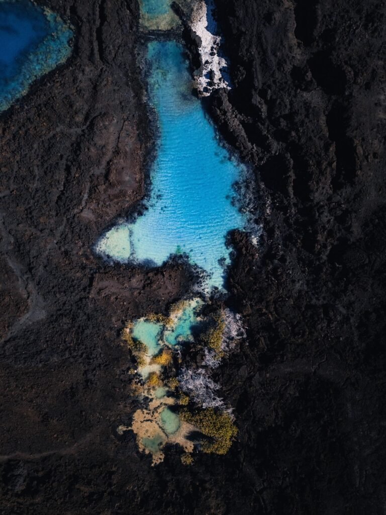 Turquoise water pools contrast dark volcanic rock.