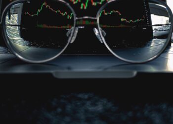 a pair of glasses sitting on top of a laptop computer