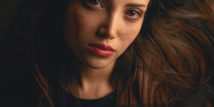 Young woman with long brown hair and freckles.