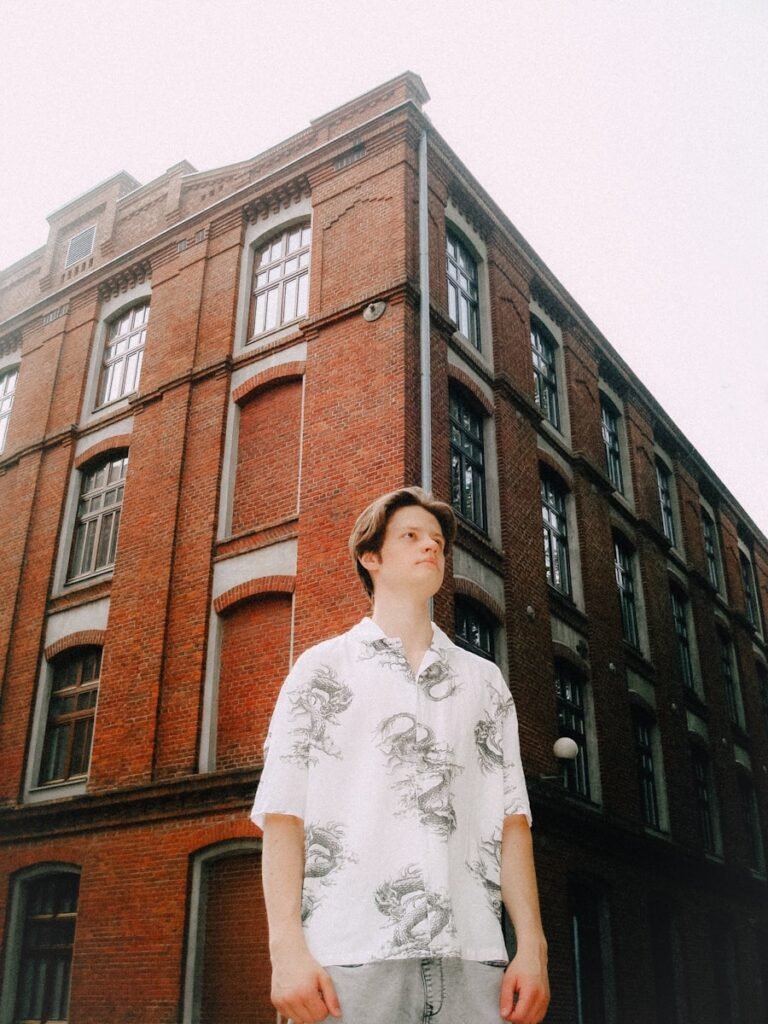 Young man stands before a brick building